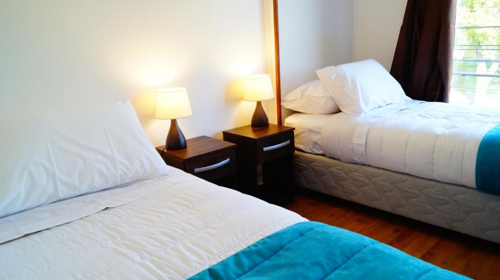 a bedroom with two beds and two lamps on tables at Haiken Hostal in Punta Arenas
