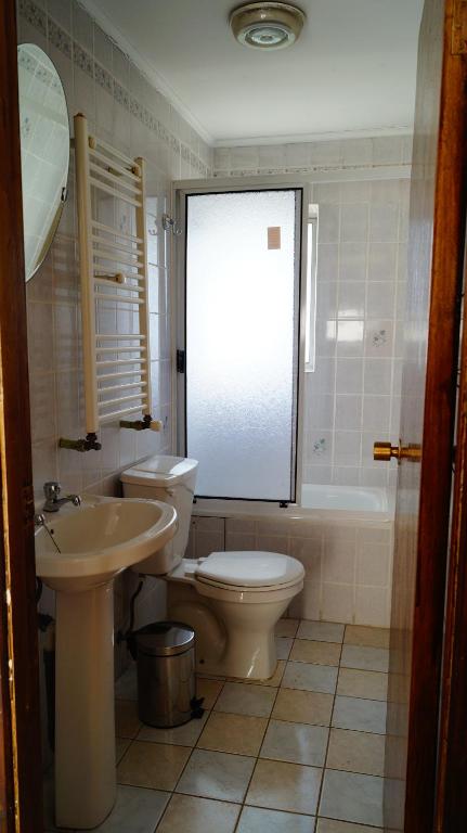 a bathroom with a toilet and a sink and a tub at Haiken Hostal in Punta Arenas