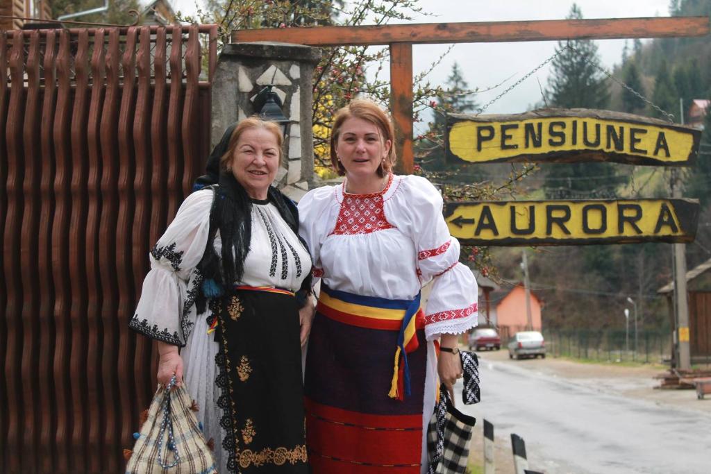 deux femmes sont debout devant un panneau dans l'établissement Pensiunea Aurora Albac, à Albac