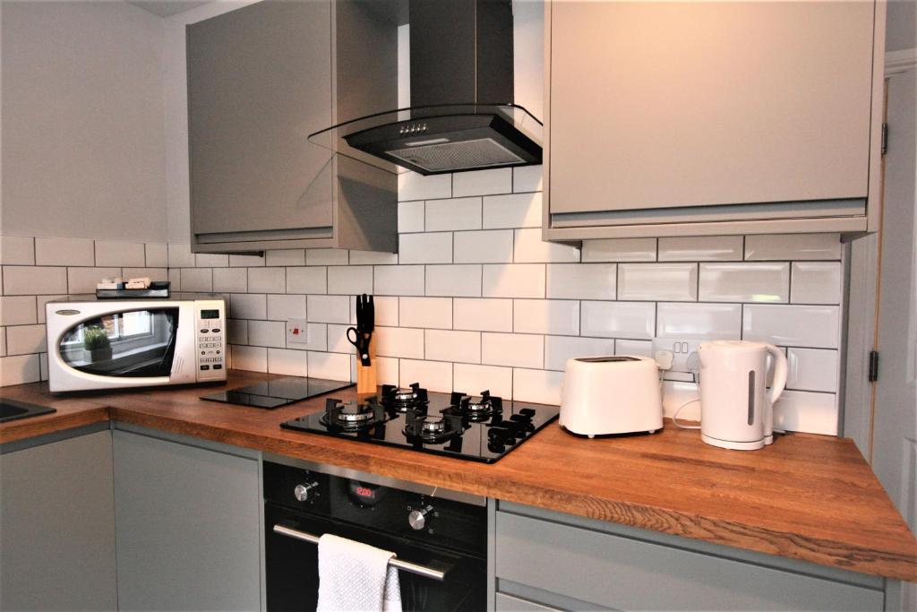 a kitchen with a stove and a microwave at Nelson By The Docks Serviced Apartments by Roomsbooked in Gloucester