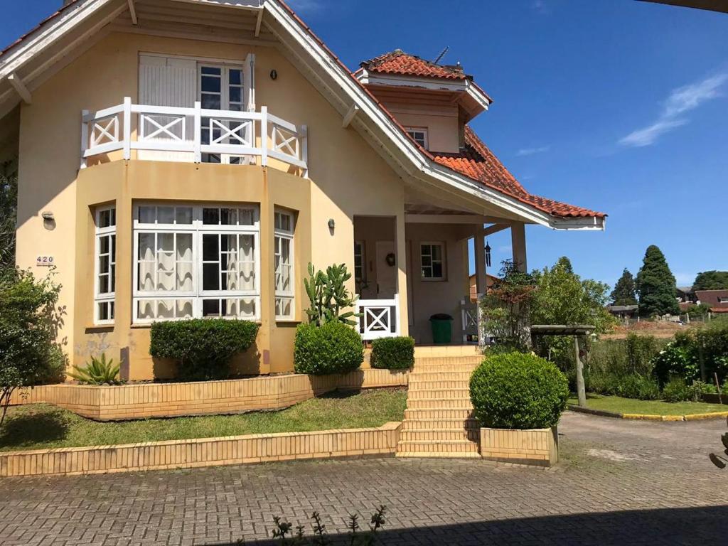 uma casa com uma grande janela e arbustos em Recanto Do Charão em Gramado