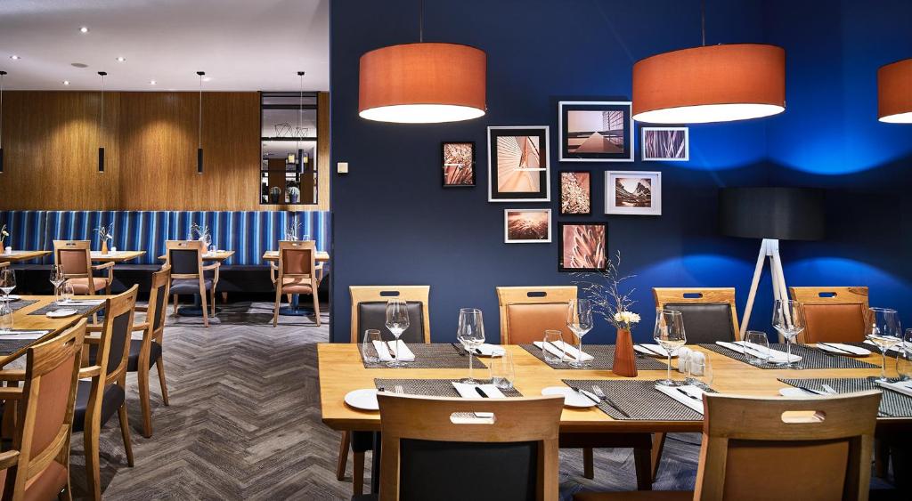 ein Restaurant mit Holztischen und -stühlen und blauen Wänden in der Unterkunft Atlanta Hotel International Leipzig in Leipzig
