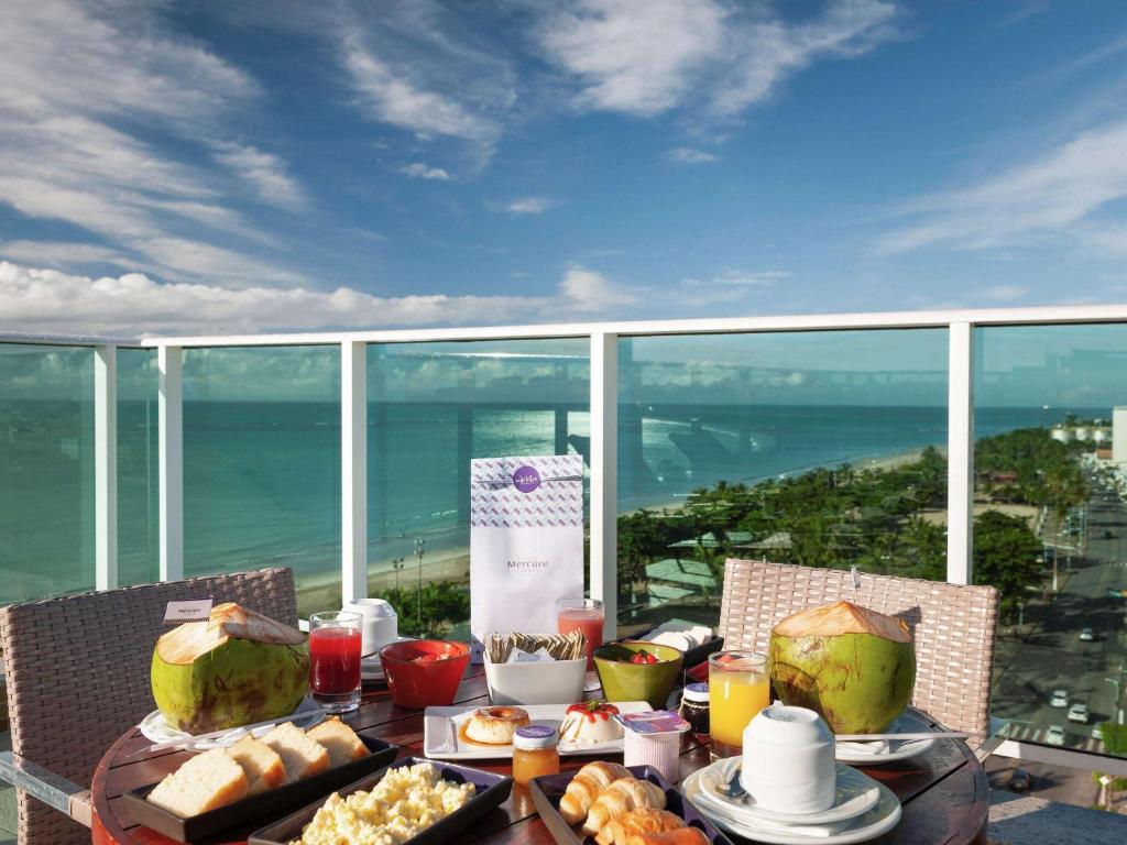 uma mesa com comida e vista para o oceano em Mercure Maceio Pajuçara em Maceió