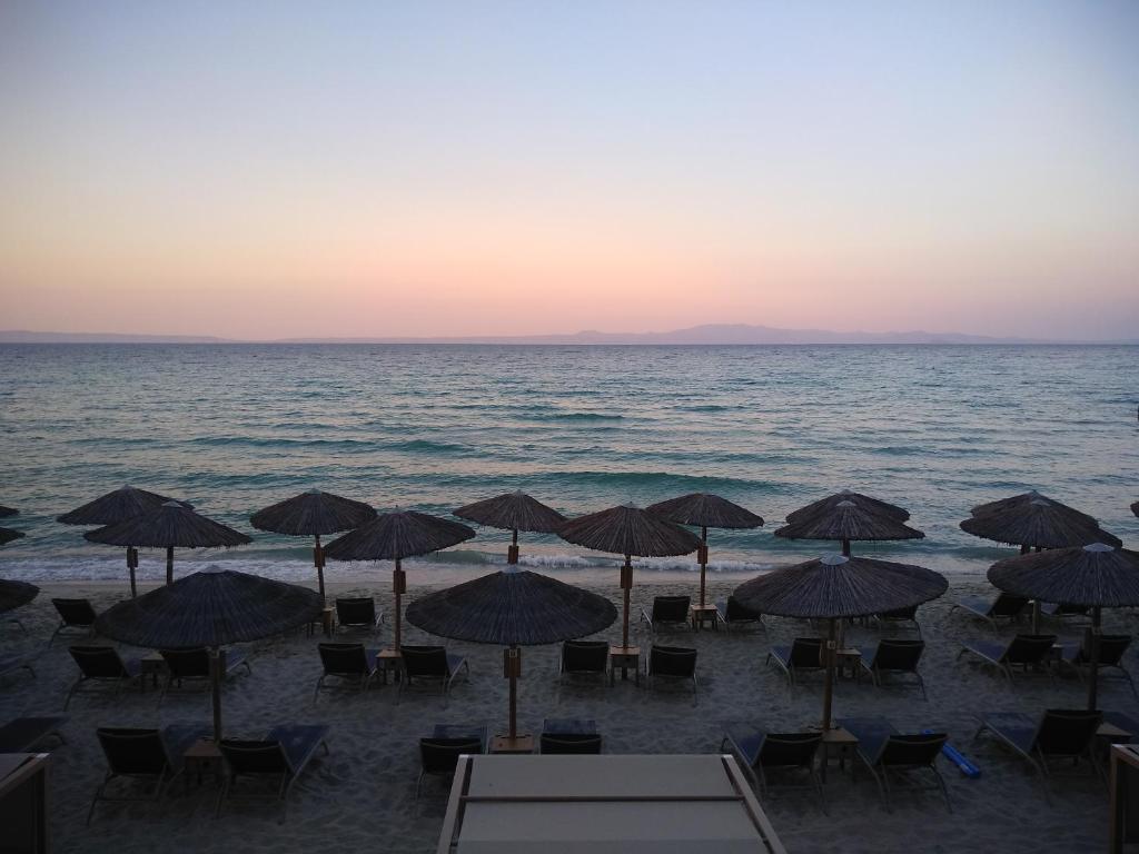 uma praia com cadeiras e guarda-sóis e o oceano em Phyllis Maisonettes em Kallithea Halkidikis