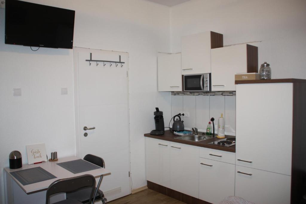 eine kleine Küche mit weißen Schränken und einem Waschbecken in der Unterkunft Ferienwohnung Möwennest I in Emden