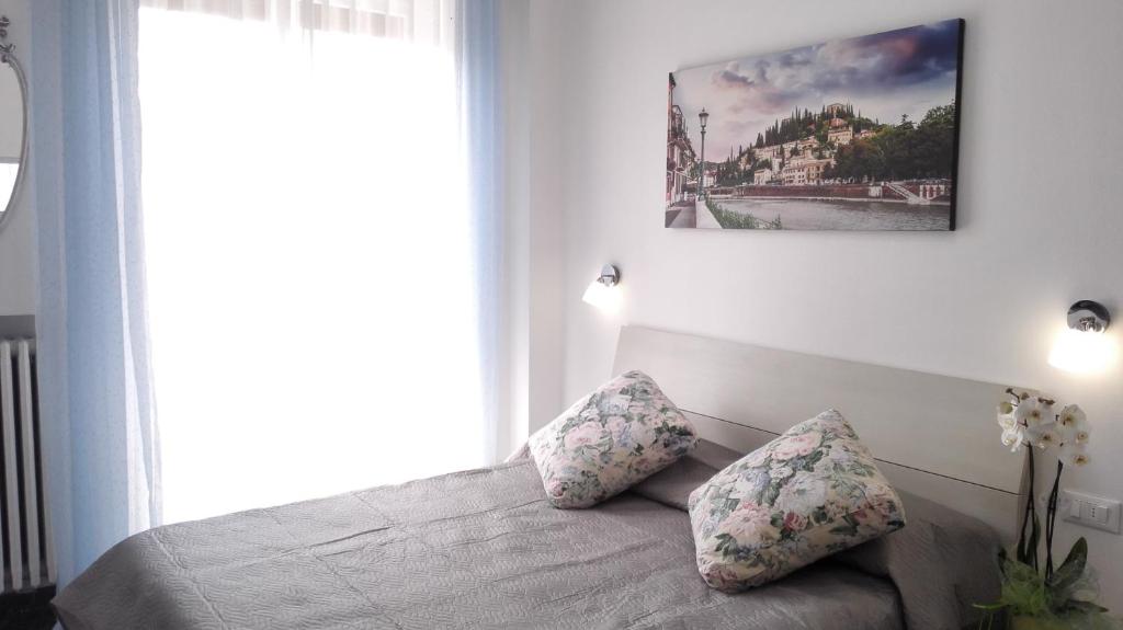 1 dormitorio con 1 cama con 2 almohadas y ventana en MinihouseLarissa diVerona, en Verona
