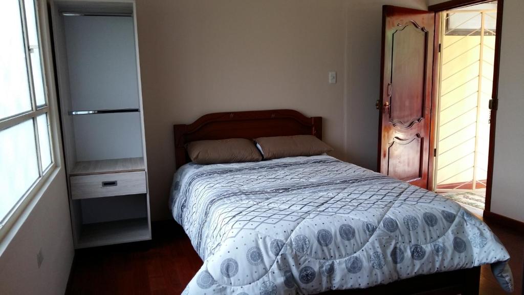 a bedroom with a bed with a white comforter at HOSPEDAJE CARIGAN in Loja