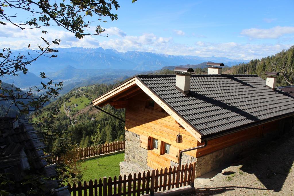 a wooden house with a roof with mountains in the background at Maso Bolpis in Trento