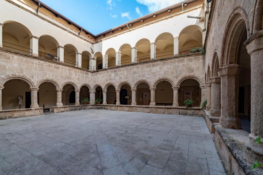 einen leeren Innenhof in einem Gebäude mit Bögen in der Unterkunft San Francesco Heritage Hotel in Alghero