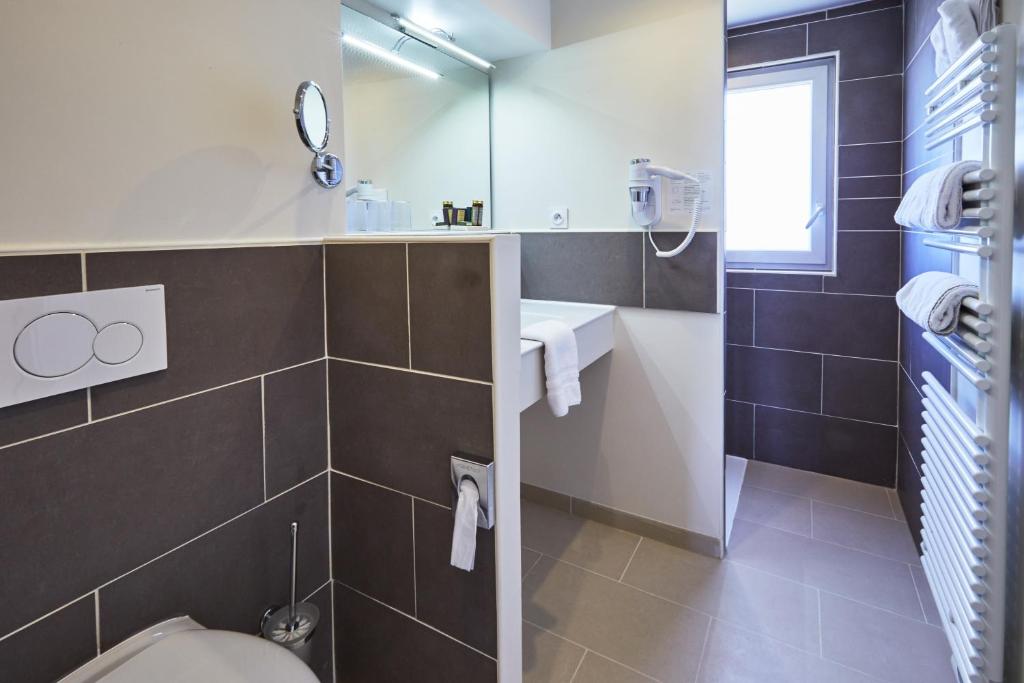 a bathroom with a toilet and a sink and a mirror at Les Villas d'Arromanches, Teritoria in Arromanches-les-Bains