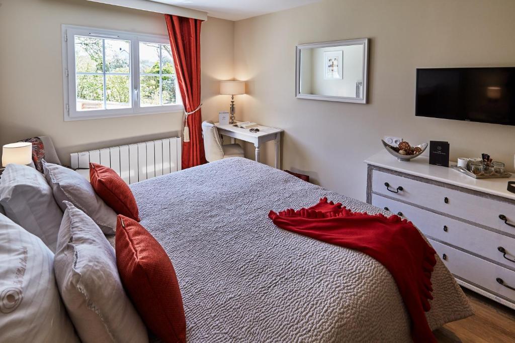 a bedroom with a bed with red pillows and a television at Les Villas d'Arromanches, Teritoria in Arromanches-les-Bains