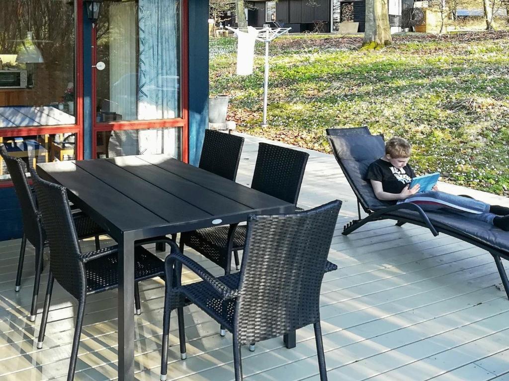 un garçon assis sur une chaise avec un ordinateur portable sur une table dans l'établissement 5 person holiday home in TJ RNARP, à Tjörnarp