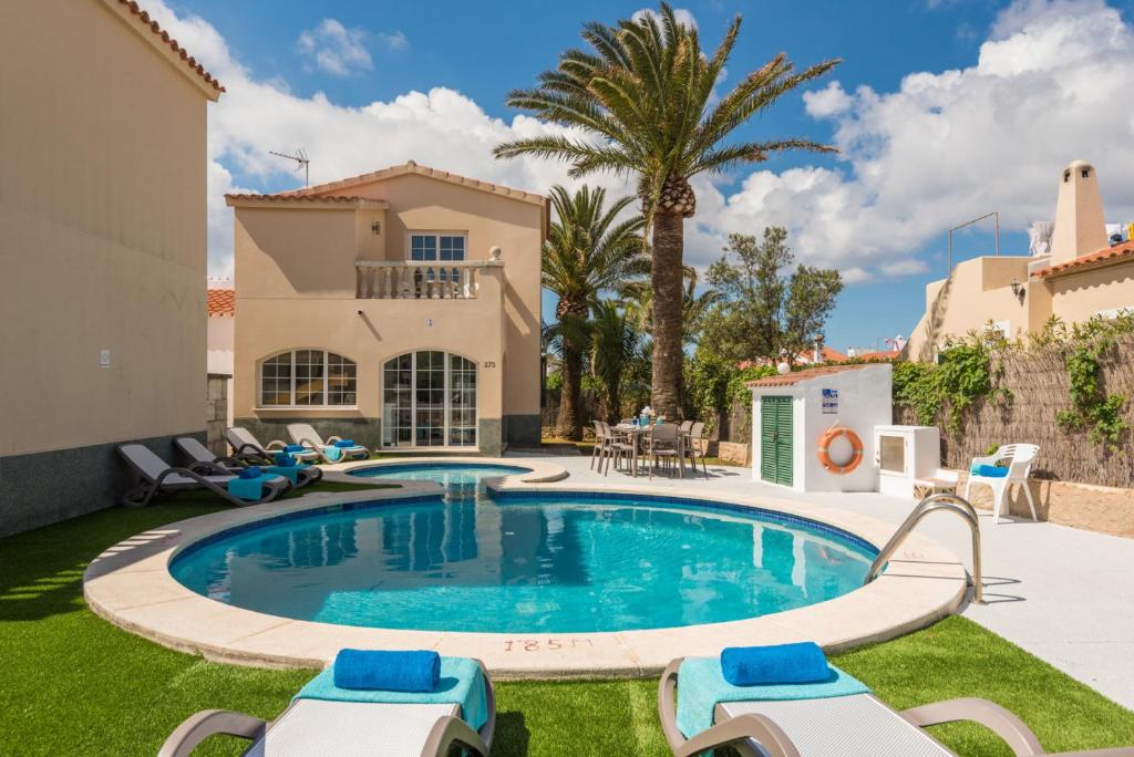 a swimming pool in a backyard with chairs and a house at VILLA CARYANA II in Cala en Blanes