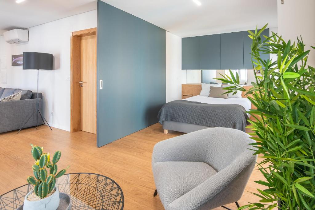 Vista Lisboa Guest Apartments في ألمادا: غرفة نوم بسرير وكرسي والنباتات