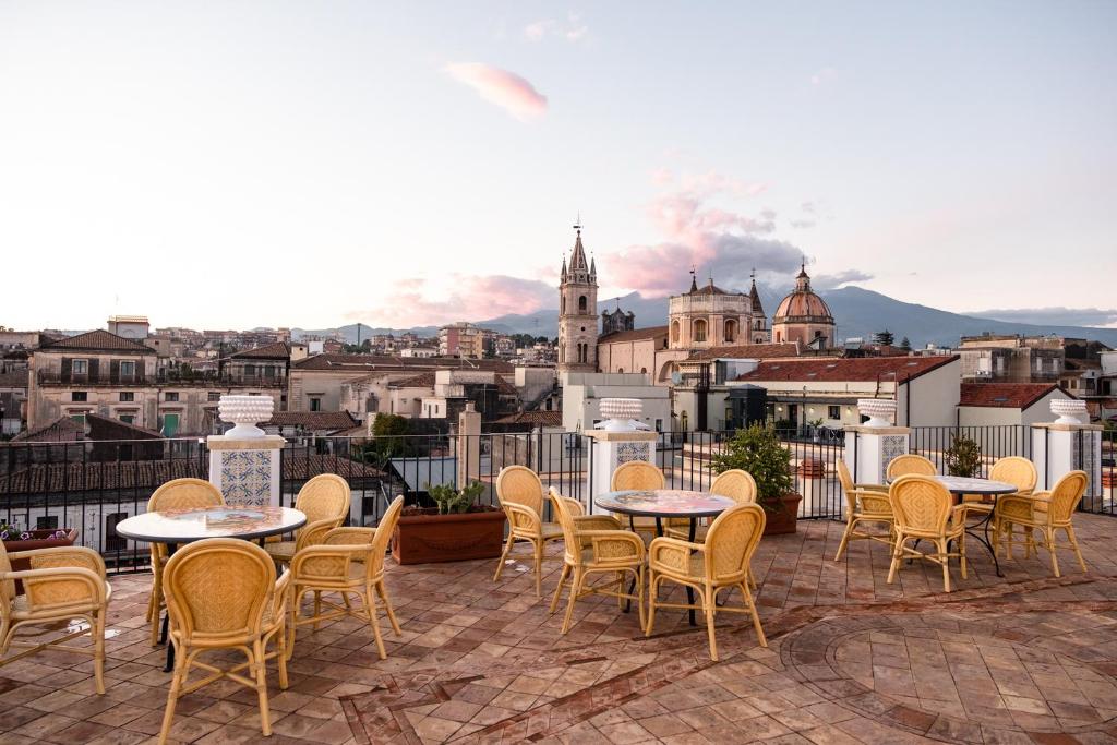 a patio with tables and chairs and a view of a city at Raciti Palace in Acireale