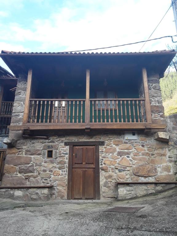 a stone house with a balcony and a wooden door at Casa Matilde in Proaza