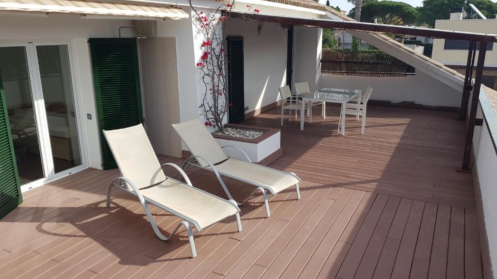 una terrazza con sedie bianche, tavolo e sedie di Encantador apartamento en S'Agaró-Platja de Aro a S'Agaró