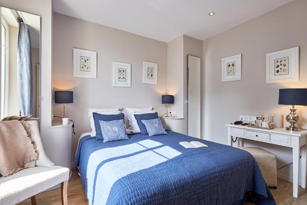 a bedroom with a blue bed and a chair at Les Villas d'Arromanches, Teritoria in Arromanches-les-Bains