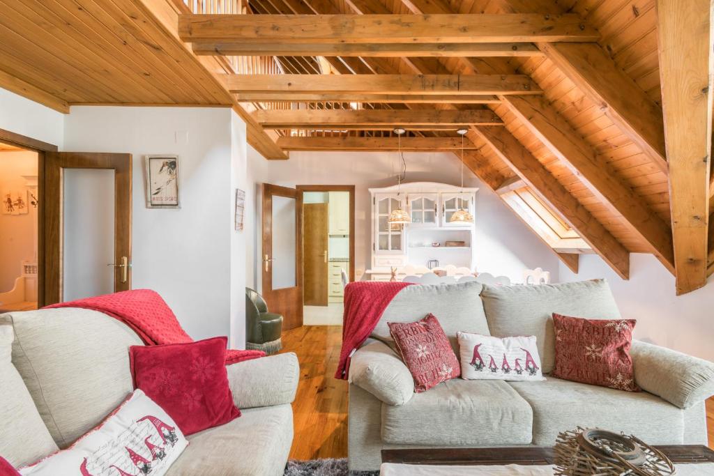 a living room with two white couches and red pillows at Montcorbison by Totiaran in Vielha