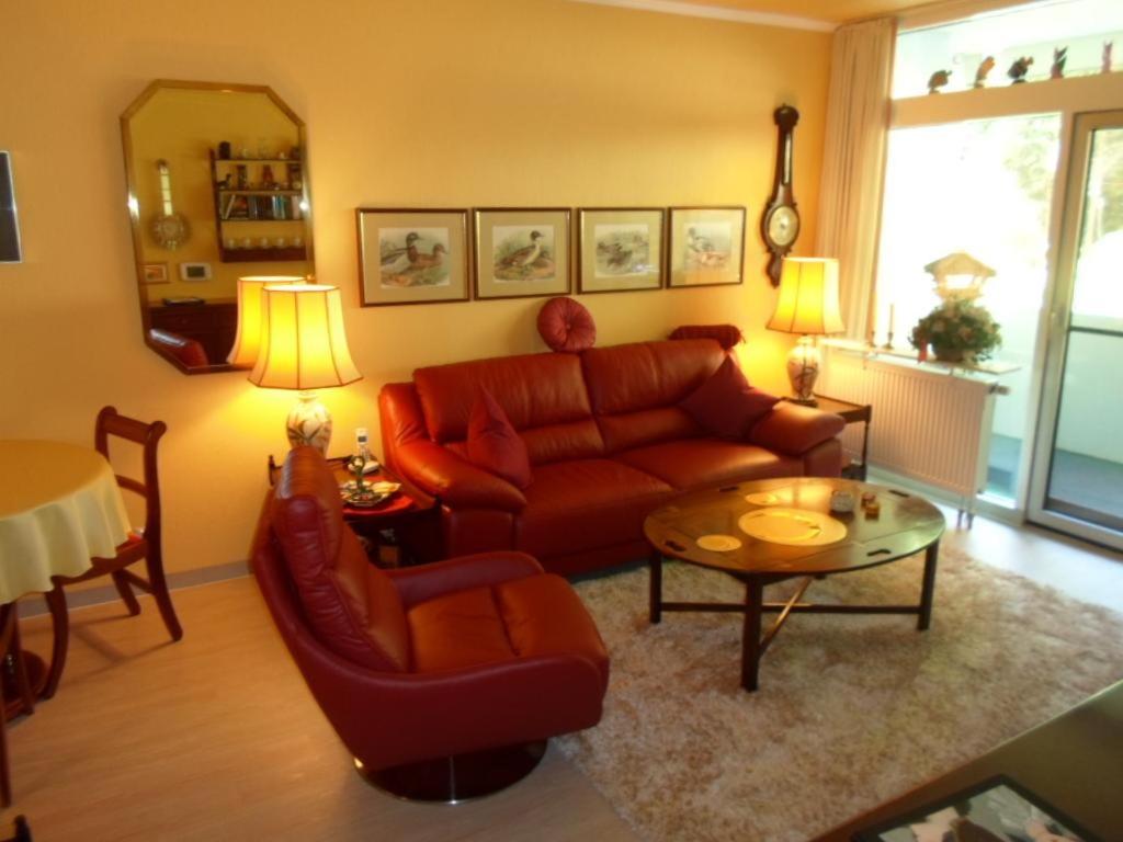 ein Wohnzimmer mit einem roten Sofa und einem Tisch in der Unterkunft 3 echte DTV Sterne FeWo Münster mit Saunen, Schwimmbad & WLAN! in Bad Harzburg