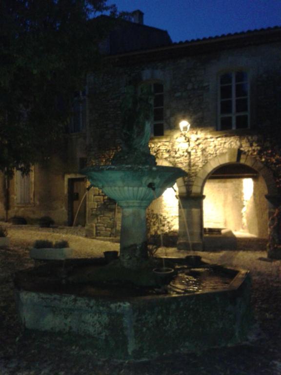 uma fonte em frente a um edifício à noite em À l'étape des jeunes randonneurs un adulte un enfant em Saignon