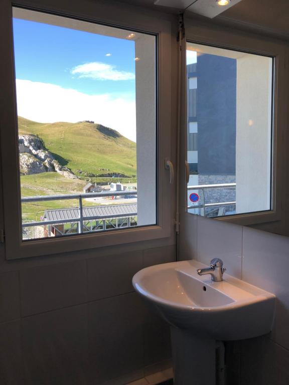 La salle de bains est pourvue d'un lavabo et d'une fenêtre avec vue. dans l'établissement Appartements du Pic d'Anie, à Arette