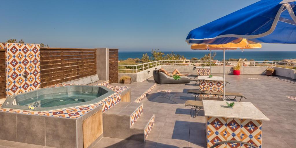 a hot tub on a patio with the ocean in the background at THE BONGOS - Socially Conscious Rooms, Part of the room rate goes to charity in Maleme