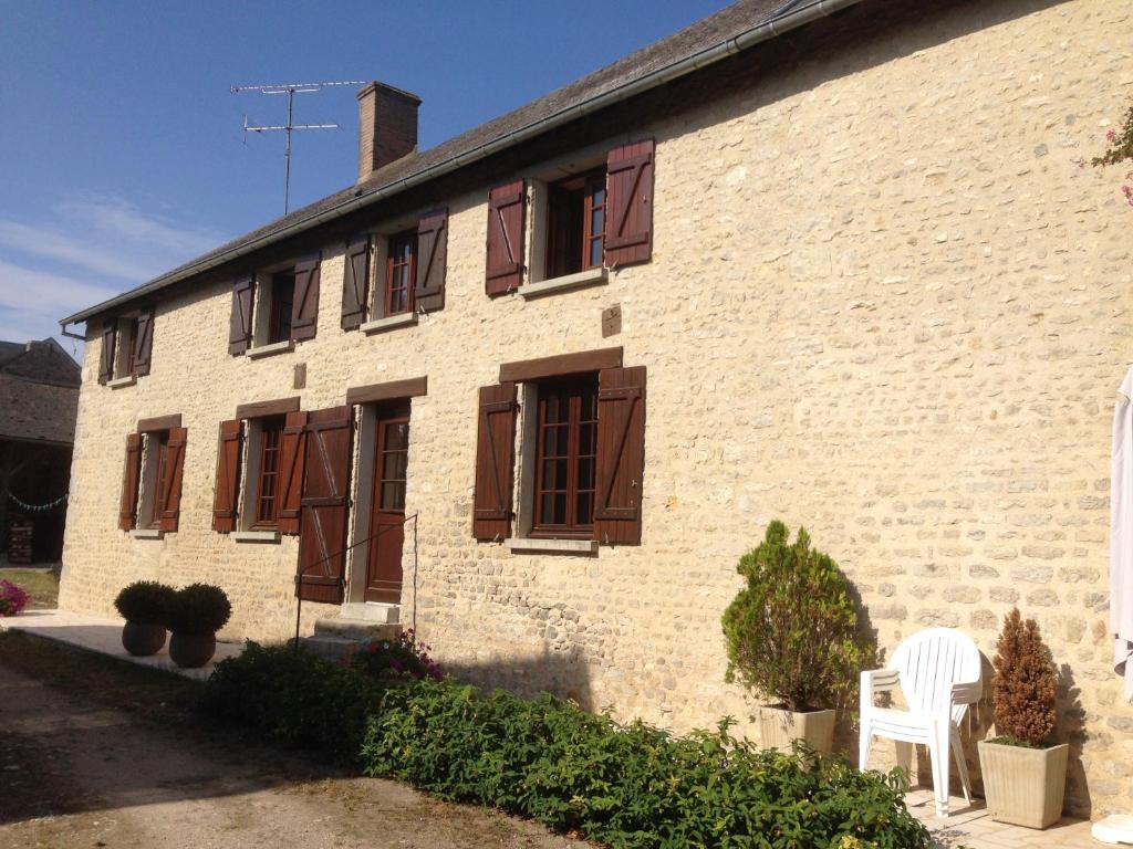 a building with brown shuttered windows and a white chair at Appart dans fermette in Audeville