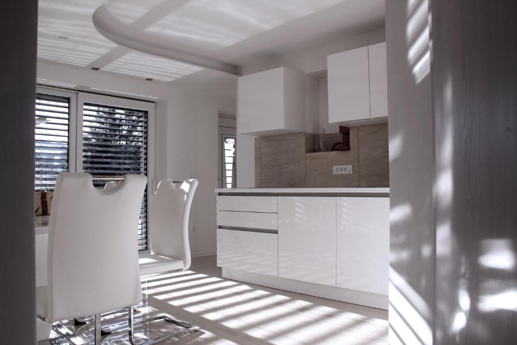 una cocina blanca con armarios blancos y sillas blancas en Deluxe Apartments Panorama, en Lesce