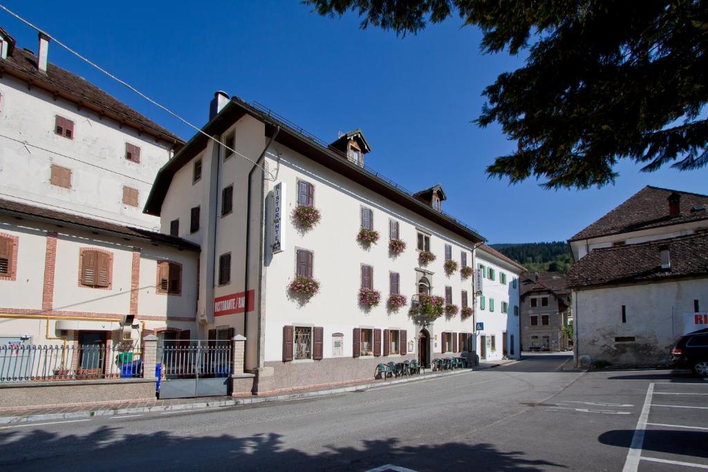 a large white building with flowers on the windows at Albergo Alle Alpi in Comeglians