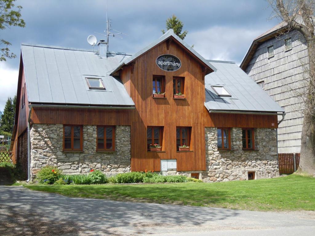 a large wooden building with a gambrel roof at Apartmány Nové Hutě in Nové Hutě