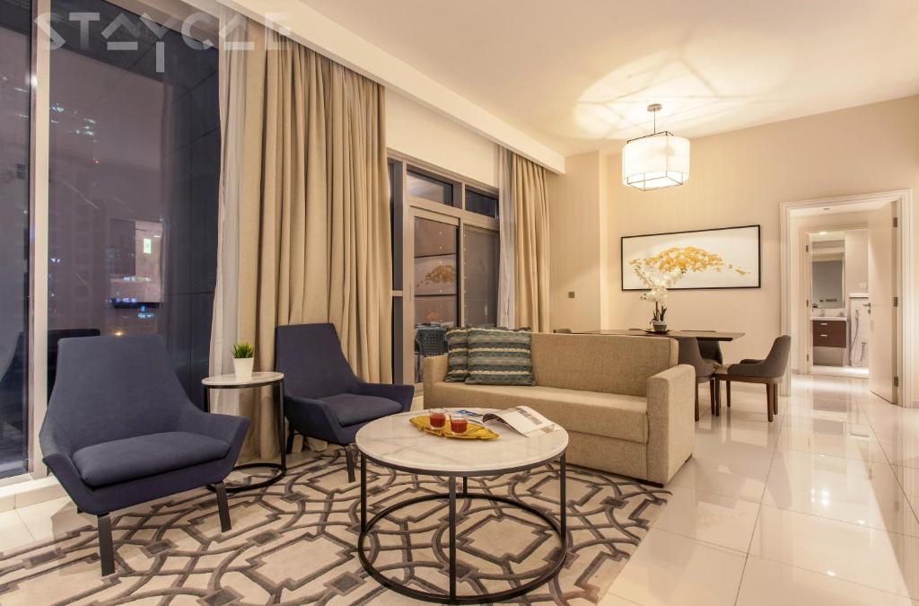 uma sala de estar com um sofá, cadeiras e uma mesa em Staycae Avanti em Dubai