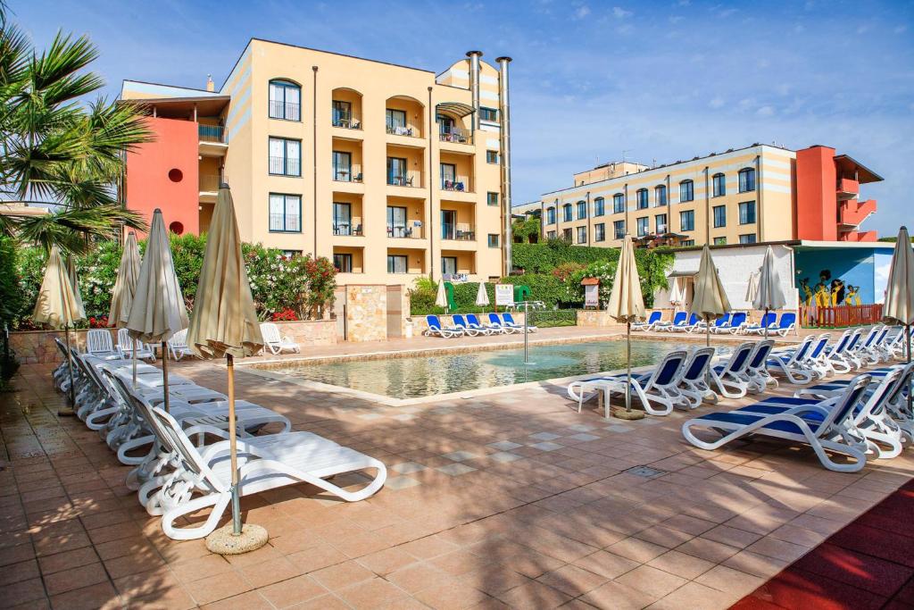 um grupo de espreguiçadeiras e guarda-sóis ao lado de uma piscina em Hotel Caesar Palace em Giardini Naxos