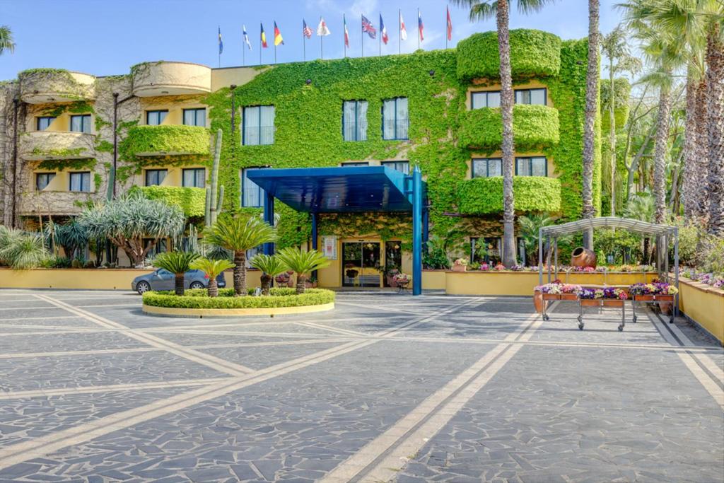 a hotel with a green ivy covered building at Hotel Caesar Palace in Giardini Naxos