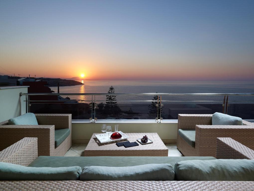 un balcón con vistas al océano al atardecer en Macaris Suites & Spa, en Rethymno