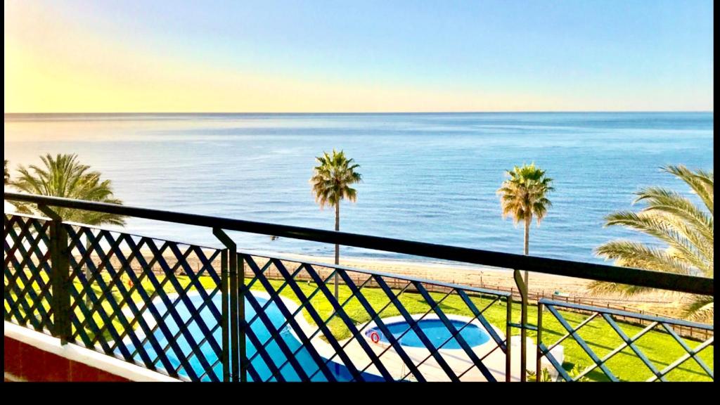 uma varanda com vista para o oceano e para as palmeiras em MI CAPRICHO B12 - Beachfront Apartment- Costa del Sol em Mijas Costa