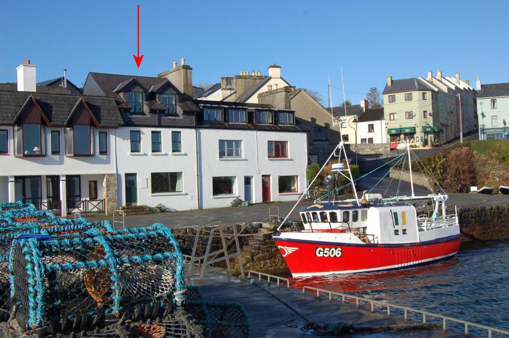 a red and white boat is docked in the water at Roundstone Quay House in Roundstone