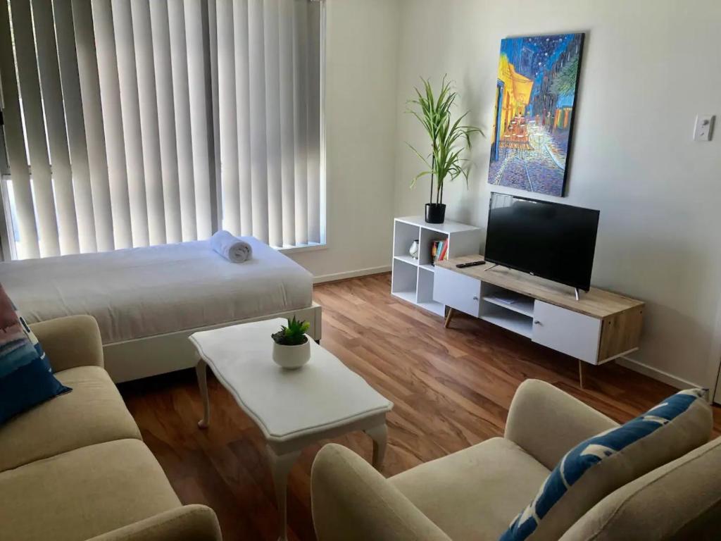 Bright 1 Bedroom Apartment 5km to Surfers Paradise في غولد كوست: غرفة معيشة مع سرير وتلفزيون