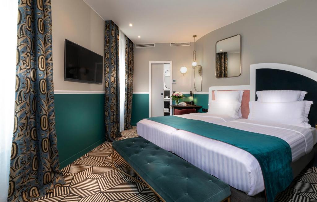 a hotel room with a large bed with a green and white bedvisor at Hotel Elysa-Luxembourg in Paris