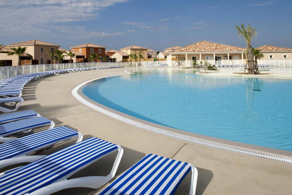 a swimming pool with blue and white chaise lounge chairs at Le Domaine du Golf*** by Ateya Vacances in Fabrègues