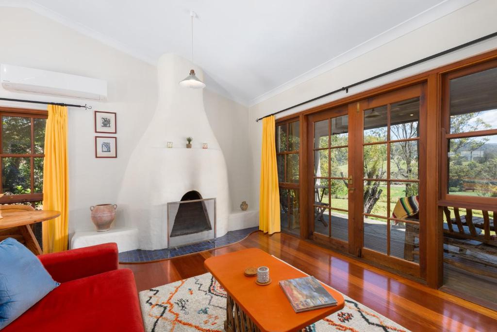 a living room with a red couch and a fireplace at Friday Creek Retreat in Coffs Harbour