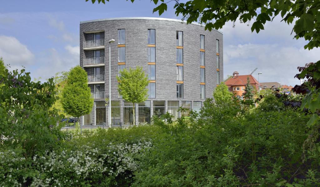 un alto edificio gris con árboles delante de él en MARA Hotel, en Ilmenau