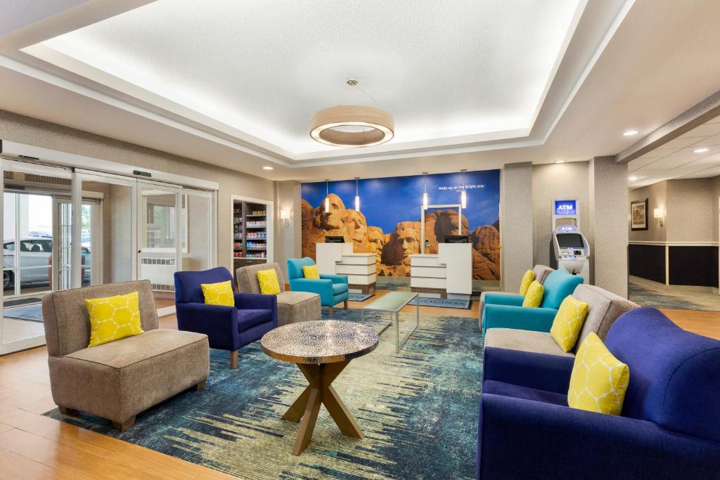 una sala de espera con sillas azules y una mesa en La Quinta by Wyndham Rapid City en Rapid City