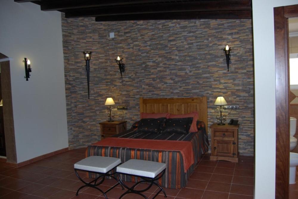 1 dormitorio con cama y pared de ladrillo en Hotel Trajano, en Zalamea de la Serena