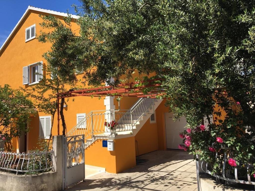 un bâtiment orange avec un escalier en face de celui-ci dans l'établissement Apartments Stuk - close to the sea, à Orebić