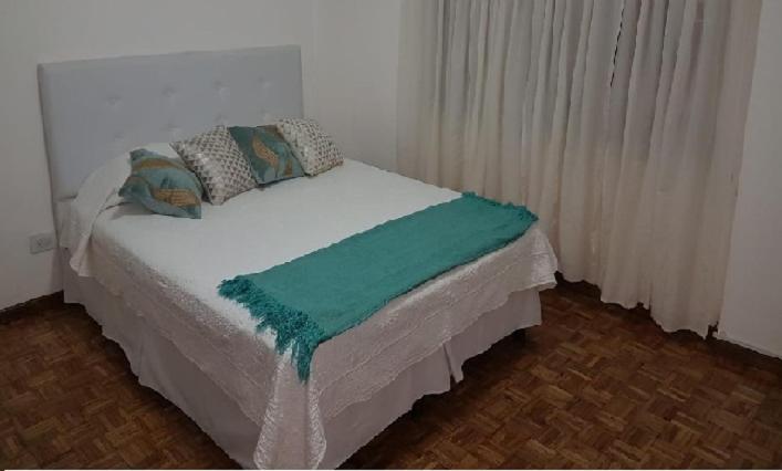 białe łóżko z zielonym kocem na górze w obiekcie Monoambiente Centro ESTRATÉGICA UBICACIÓN w BuenosAires