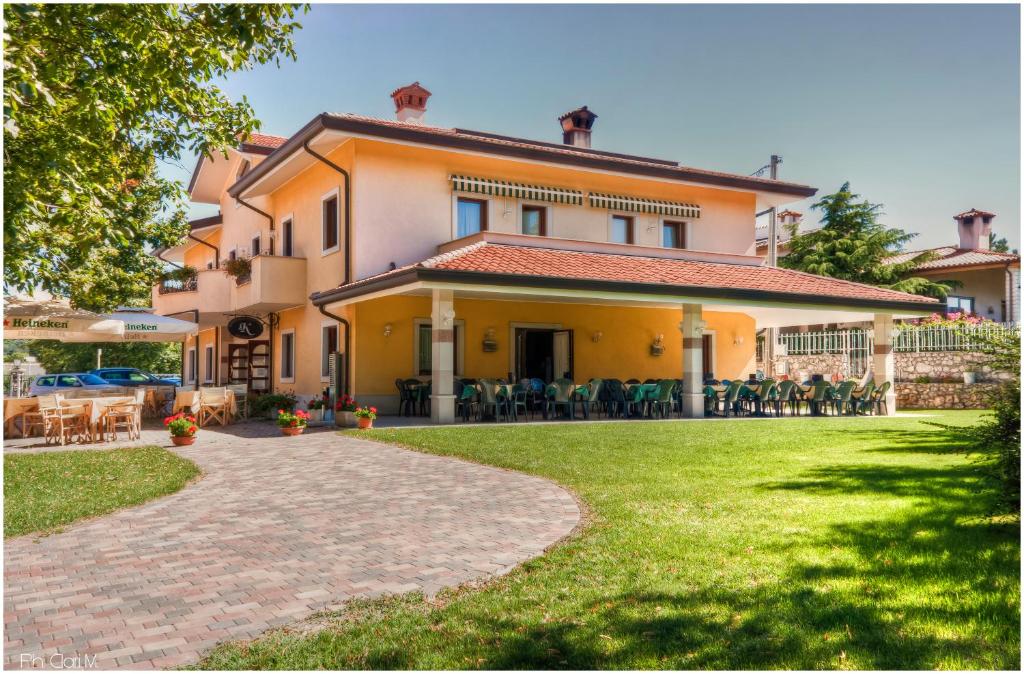 ein großes Haus mit einer Terrasse und einer Liegewiese in der Unterkunft Hotel Pesek in San Dorligo della Valle