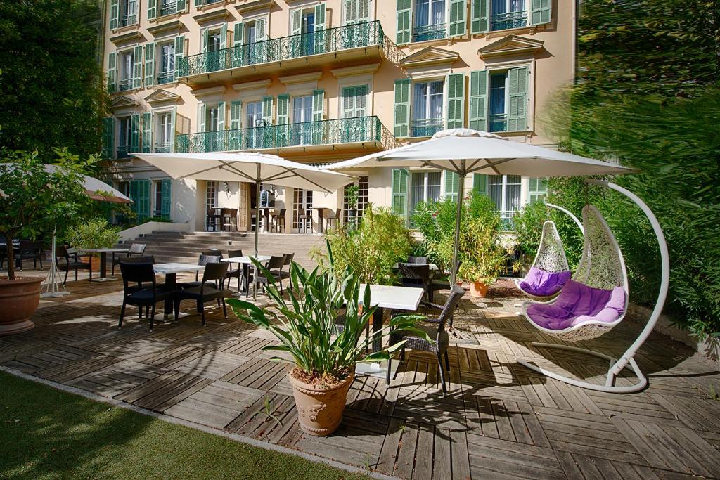 patio z krzesłami i stołami oraz budynek w obiekcie Hotel Villa Victoria w Nicei