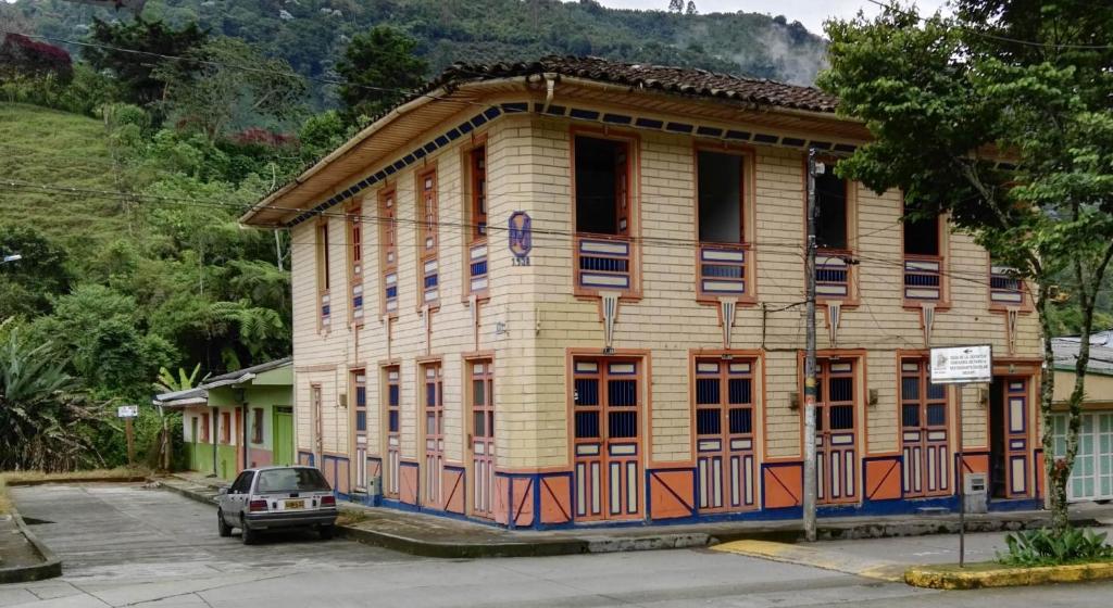 ein Holzhaus mit einem davor geparkt in der Unterkunft HOSTAL CASA VICTORIA PIJAO in Pijao