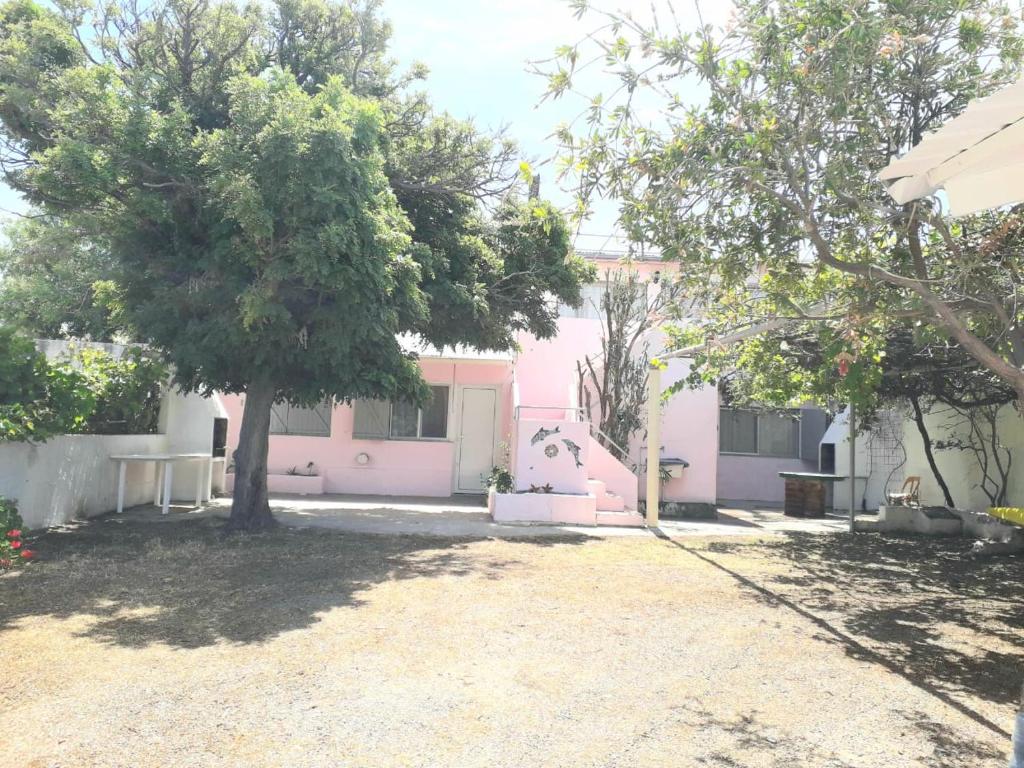una casa rosa con un árbol delante en AMANECERES LAS GRUTAS II en Las Grutas